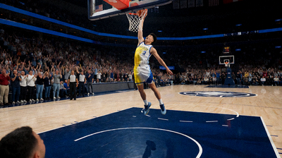 NBA篮球比赛现场，球员在球场上飞身扣篮，观众席掌声雷动，灯光聚焦在球场中央